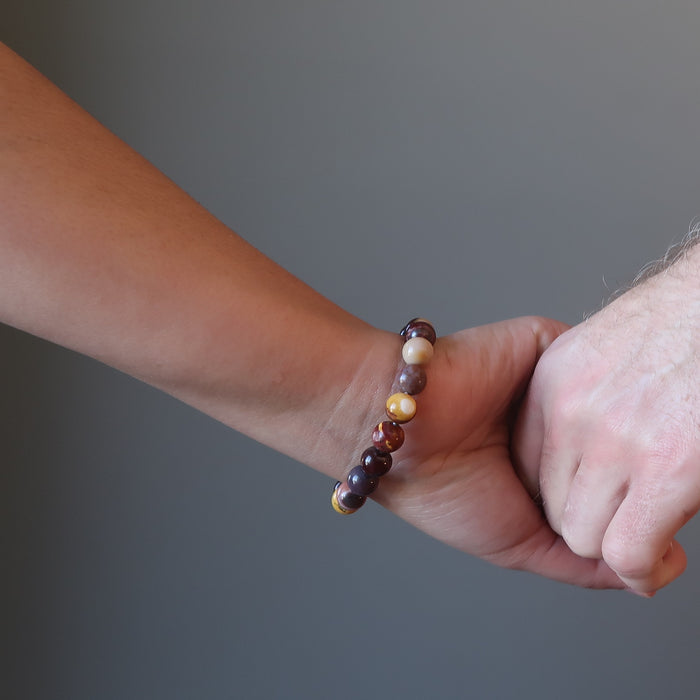 couple holding hands wearing multi colored mookaite jasper round beaded stretch bracelet