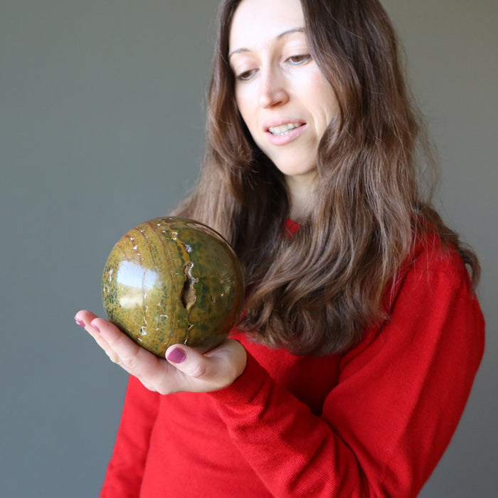 woman gazing into yellow ocean jasper sphere