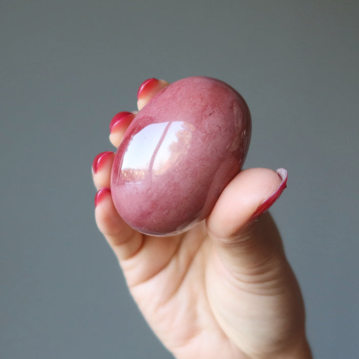 hand holding a pink mookaite jasper oval