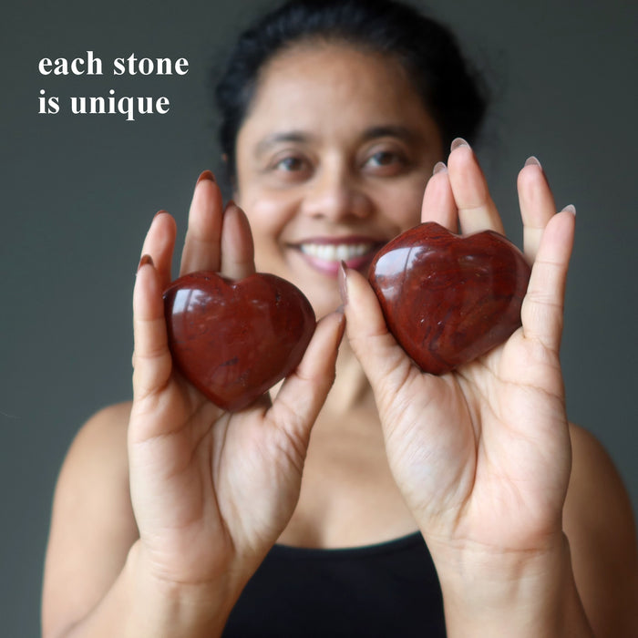 woman holding two red jasper hearts
