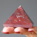 hand holding red jasper pyramid