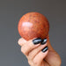hand holding a red jasper crystal ball