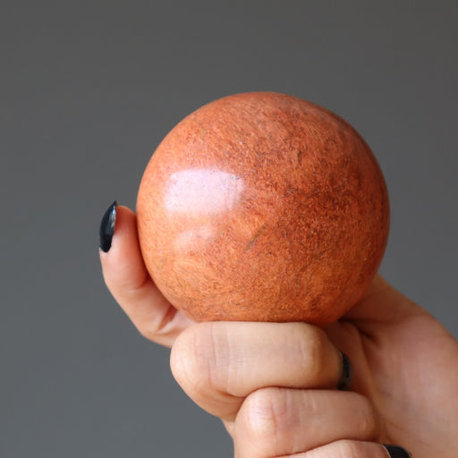 hand holding a red jasper crystal ball