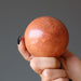 hand holding a red jasper crystal ball