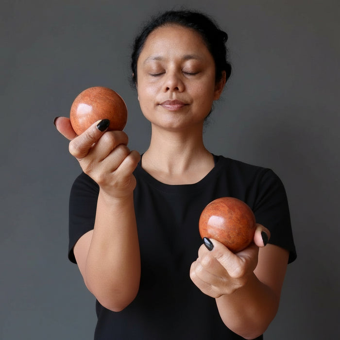 sheila of satin crystals holding 2 red jasper spheres