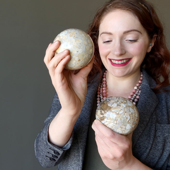 female model looking at 2 snake jasper spheres one on each hand