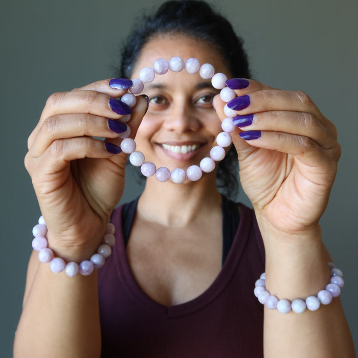 woman holding and wearing kunzite bracelets
