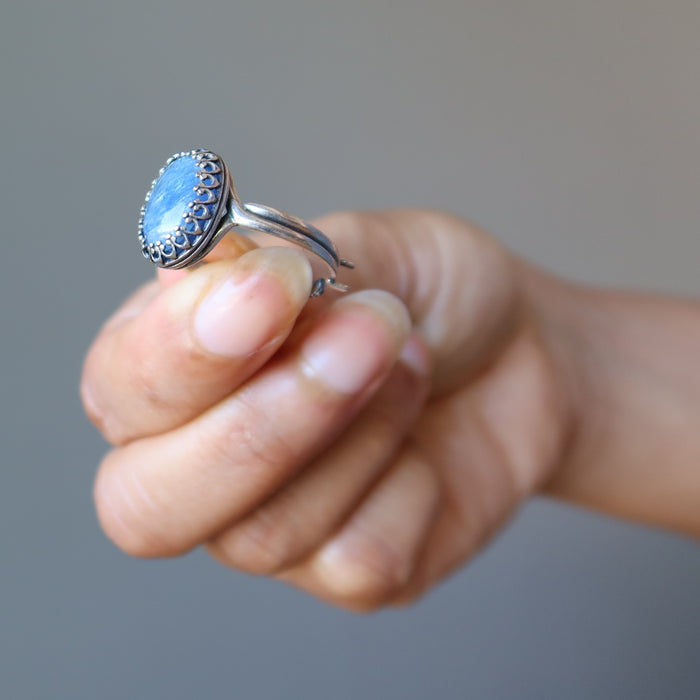 hand holding blue kyanite oval in adjustable sterling silver ring