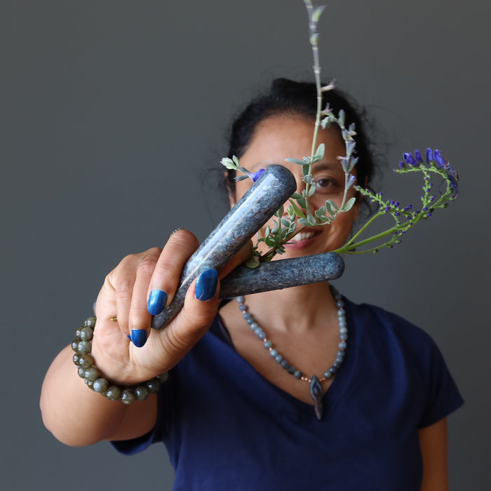 sheila of satin crystals holding two blue kyanite massage wands and flowers