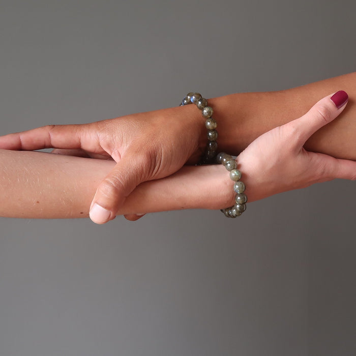 man and woman's arms wearing round labradorite beaded stretch bracelets