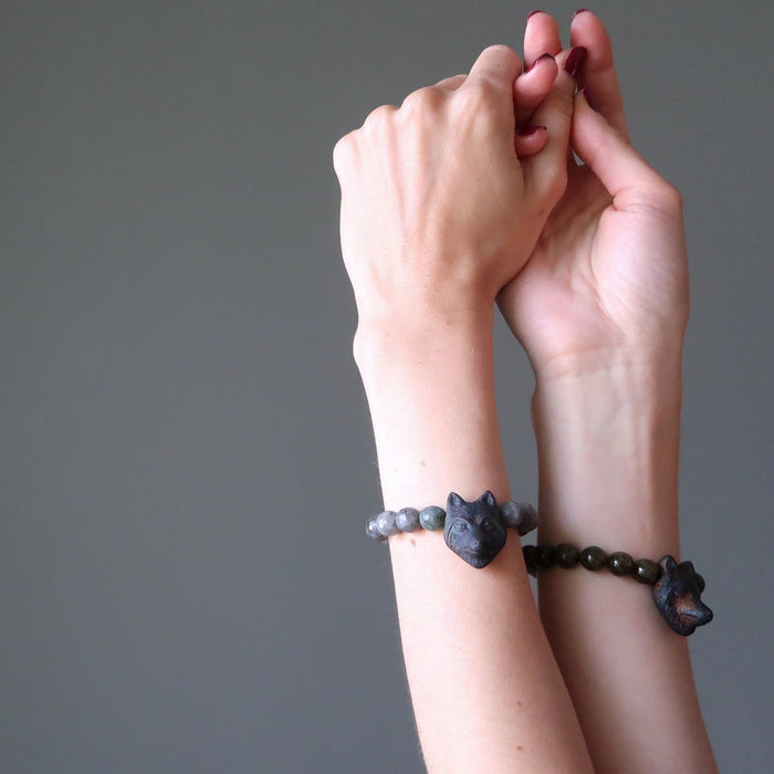 woman's hands wearing faceted labradorite and wolf head beaded stretch bracelet on each wrist