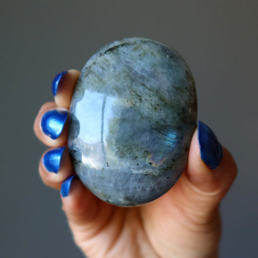 hand holding rainbow labradorite oval palm stone
