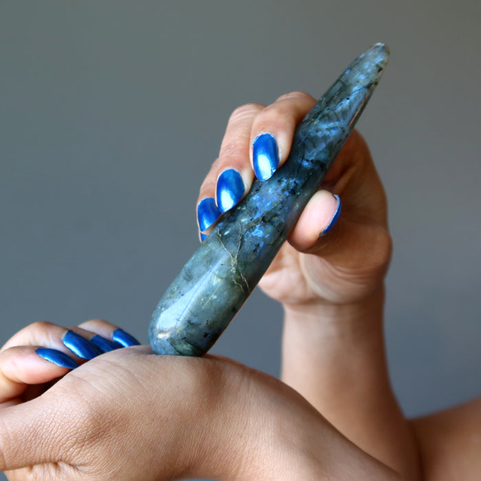 hand holding labradorite massage wand massaging wrist