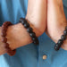 man's hand in prayer wearing red and black lava bracelet set
