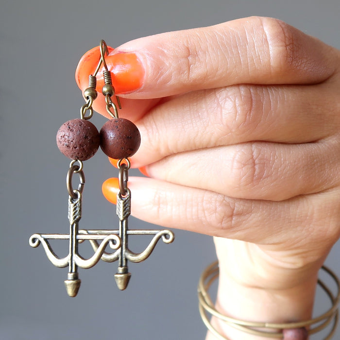 hand holding red lava bow and arrow archery dangle earrings