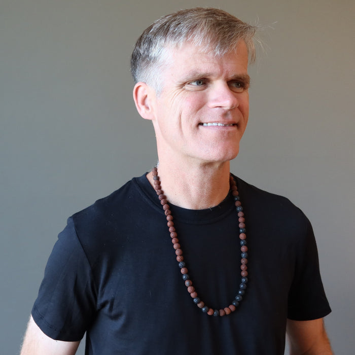 man wearing black and red lava necklace