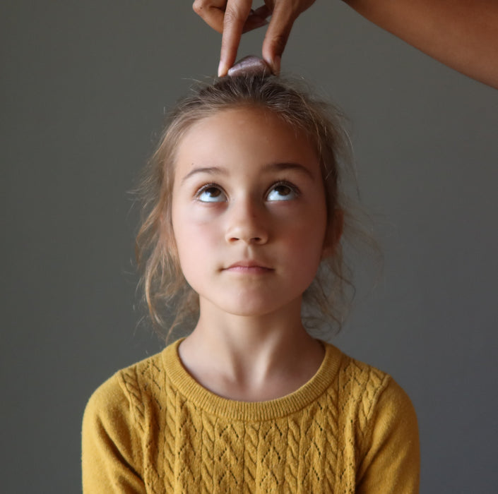 purple lepidolite tumbled stone on girls crown chakra