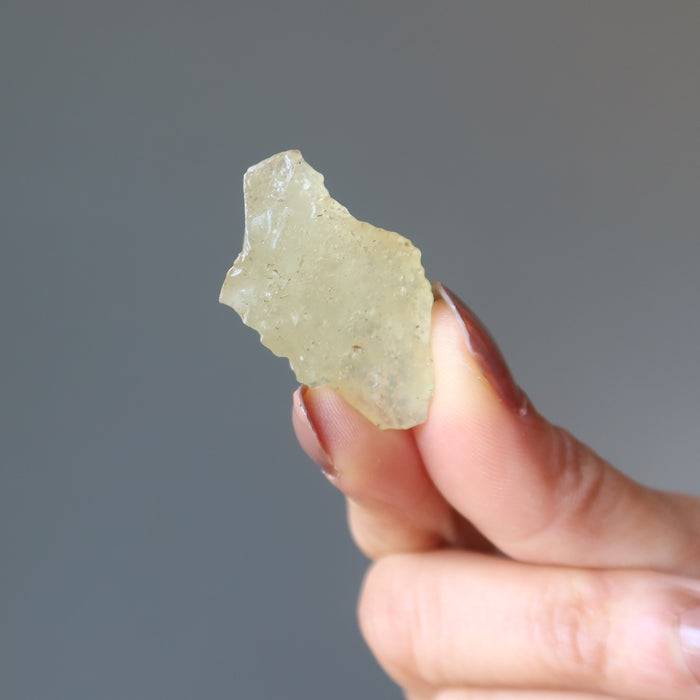fingers holding up a libyan desert glass