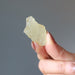 fingers holding up a libyan desert glass