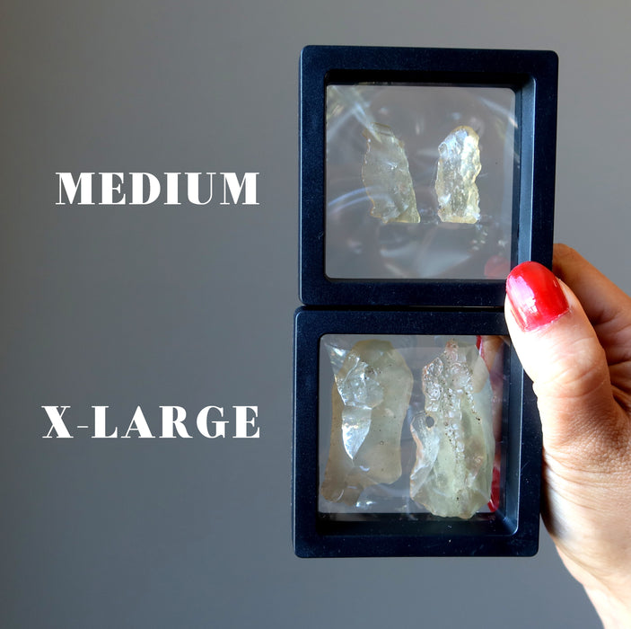 hands holding two pairs of libyan desert glass to show difference betwee medium and large sizes