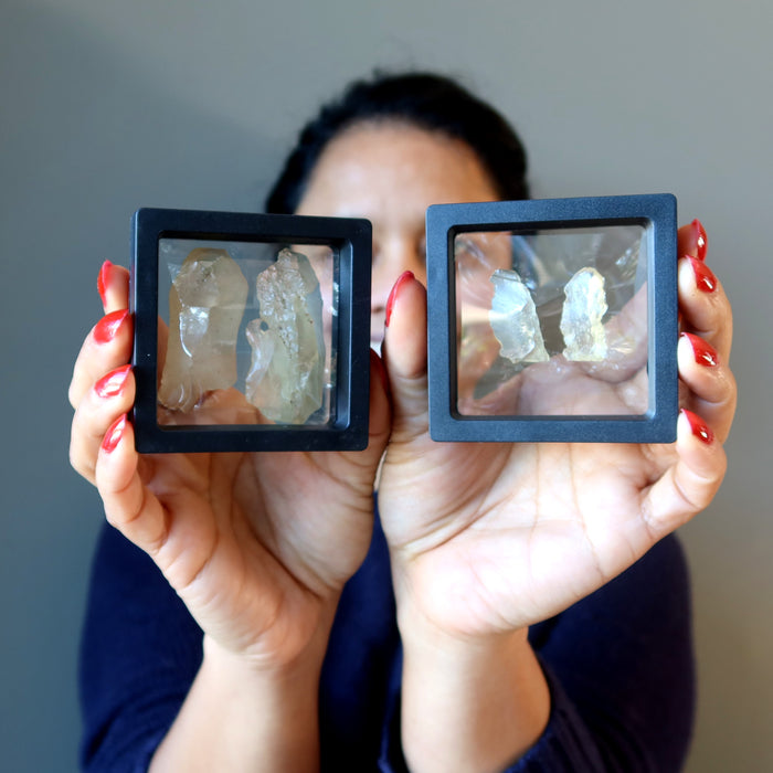 female holding two cases, each with a pair of libyan desert glass