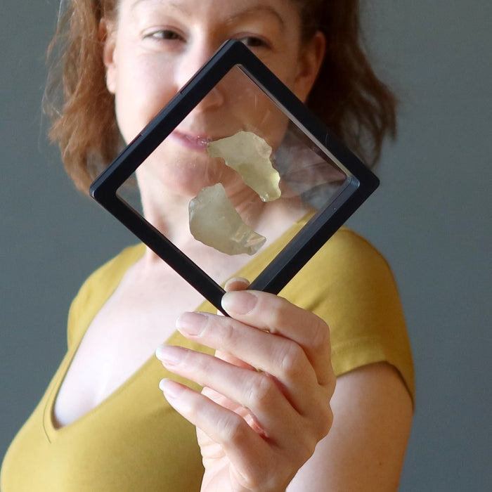 female model holding libyan desert glass pair in suspension display case