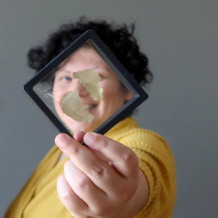 female model holding libyan desert glass pair in suspension display case