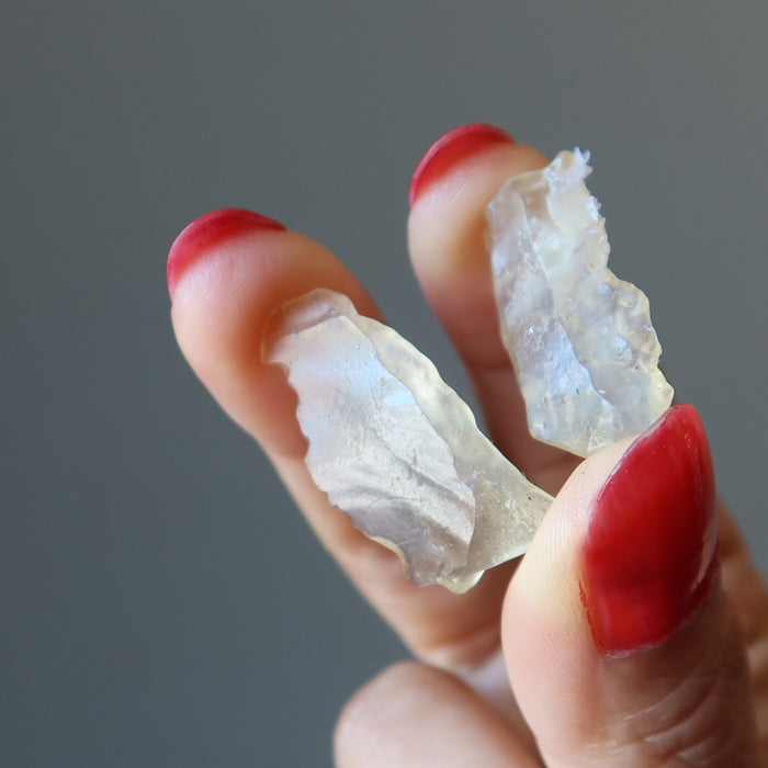 hands holding a pair of yellow libyan desert glass stones