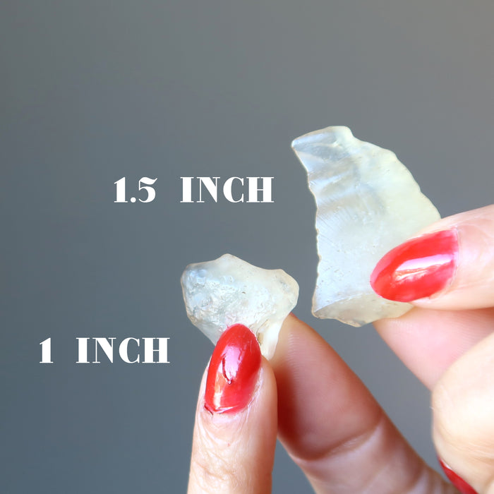 hand holding two libyan desert glass crystals to show size difference