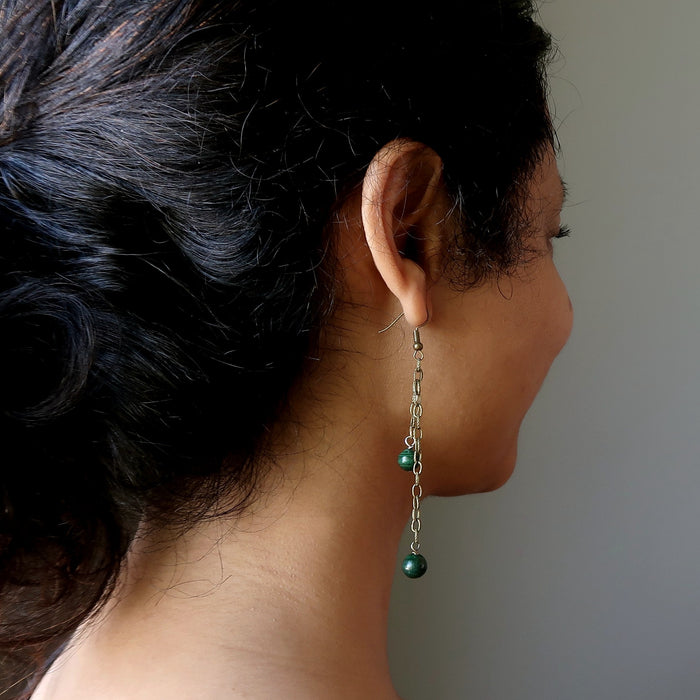 woman wearing long malachite dangle earrings