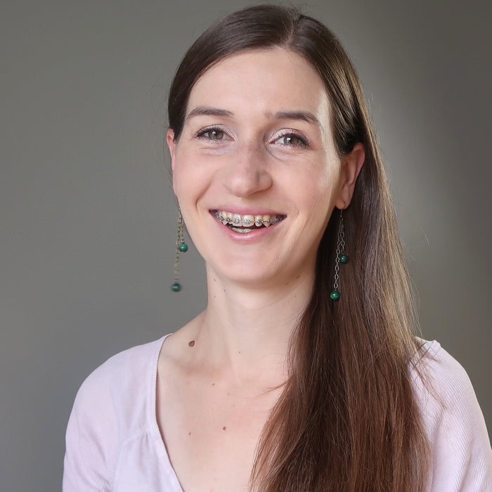 woman wearing long malachite dangle earrings