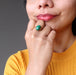 hand on chin wearing green oval malachite in gold adjustable ring
