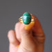 hand holding green oval malachite in gold adjustable ring