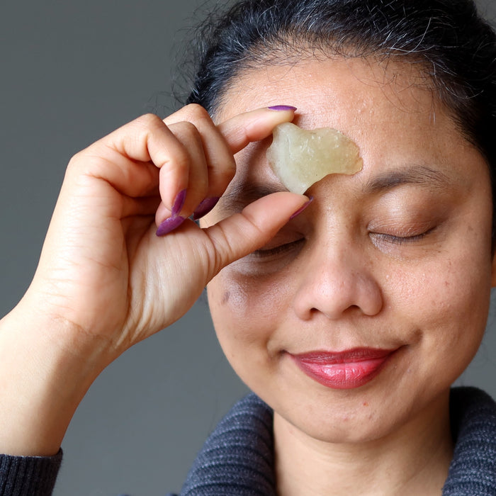 hand holding yellow libyan desert glass rough tektite to third eye chakra