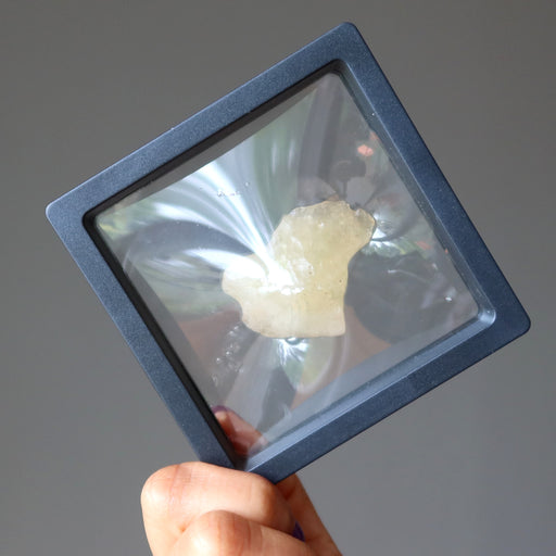 hand holding yellow libyan desert glass rough tektite in suspension case