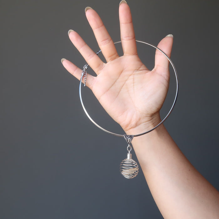 hand holding raw yellow libyan desert glass in silver cage choker necklace