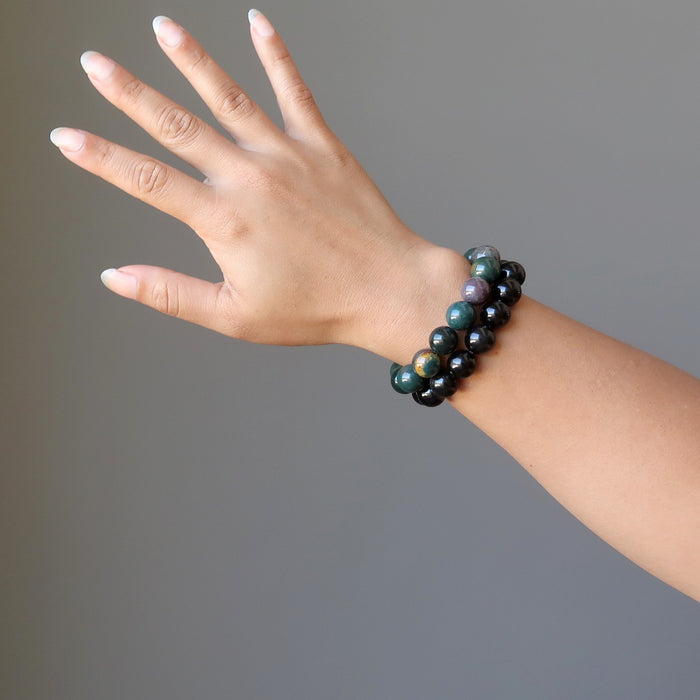 female hand modeling bloodstone and rainbow obsidian bracelet set