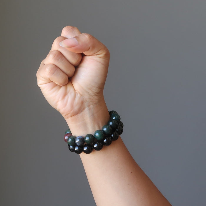 female hand modeling bloodstone and rainbow obsidian bracelet set