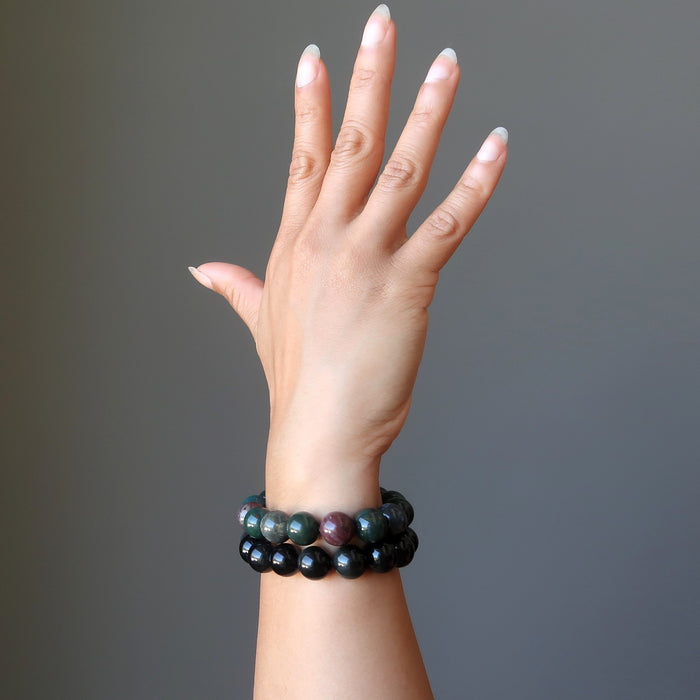 female hand modeling bloodstone and rainbow obsidian bracelet set