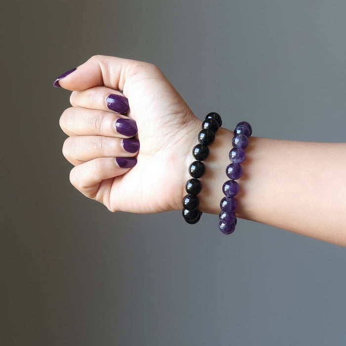 female hand wearing black tourmaline and amethyst bracelet set