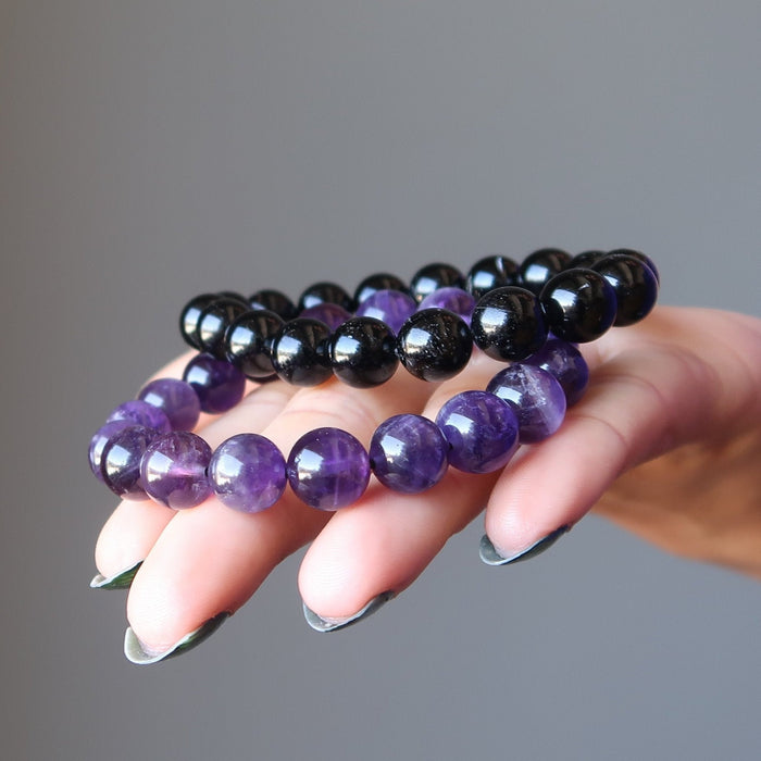 female hand with black tourmaline and amethyst bracelet set in palm