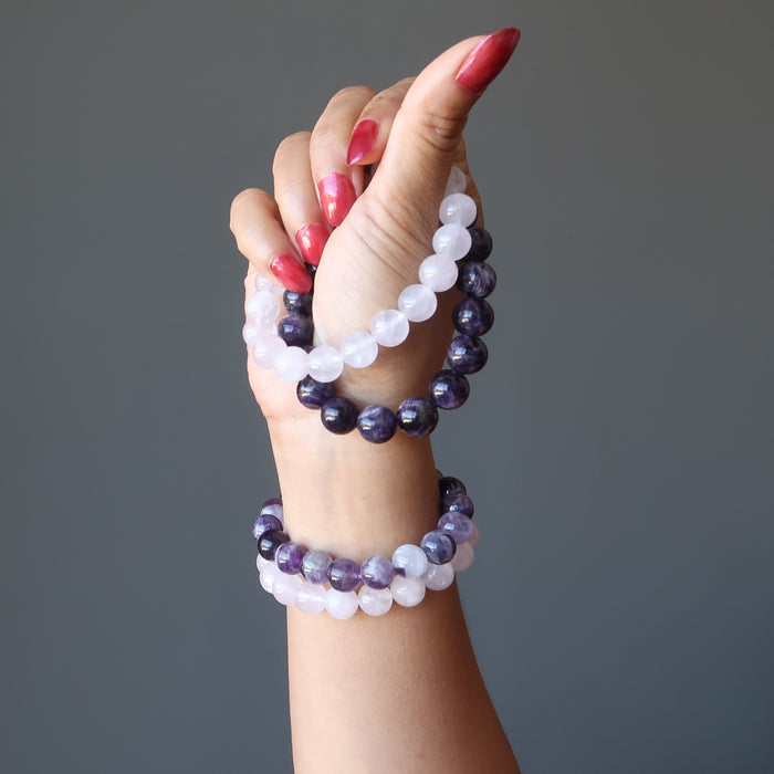 hand holding and wearing amethyst and rose quartz bracelet sets