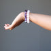 female hand wearing amethyst and rose quartz bracelet sets