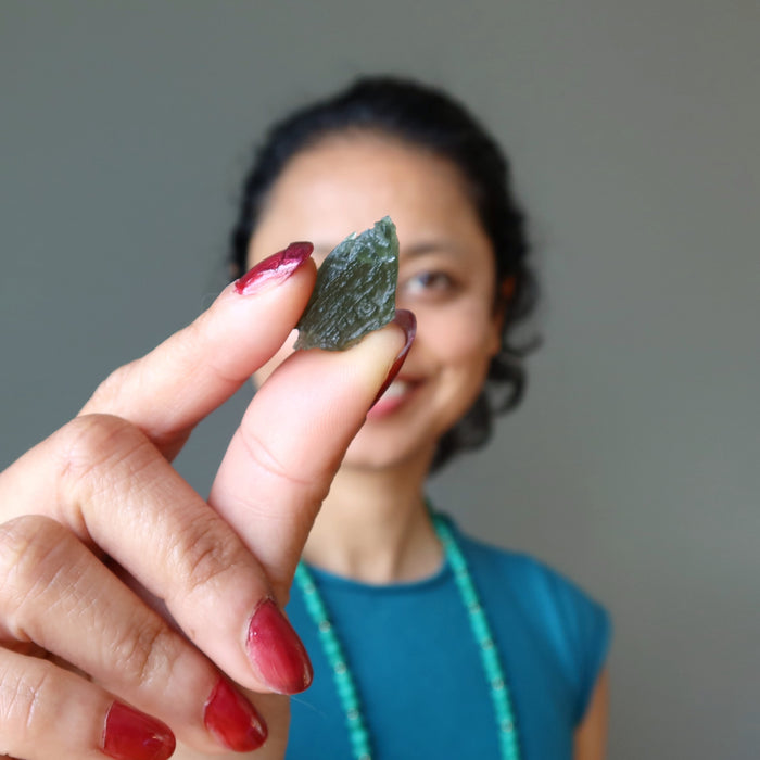 sheila of satin crystals holding up a moldavite