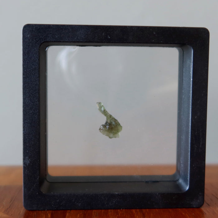 rough green moldavite gemstone in suspension display case