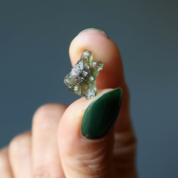 hand holding rough green moldavite gemstone