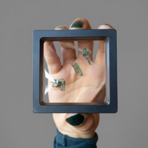 rough green moldavite gemstones in display case
