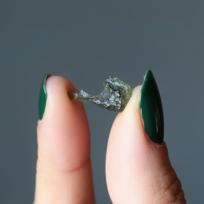 hand holding rough green moldavite gemstone