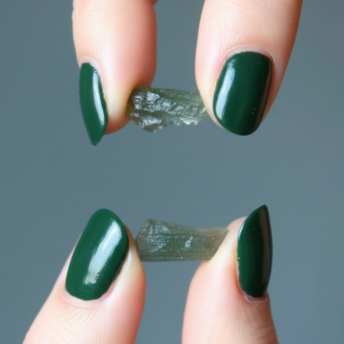 hand holding rough green moldavite gemstones