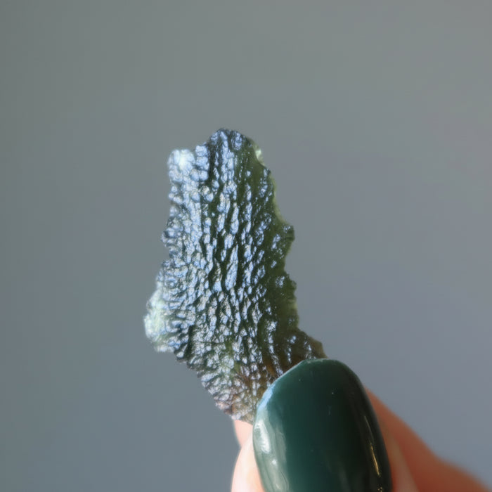 hand holding raw moldavite 